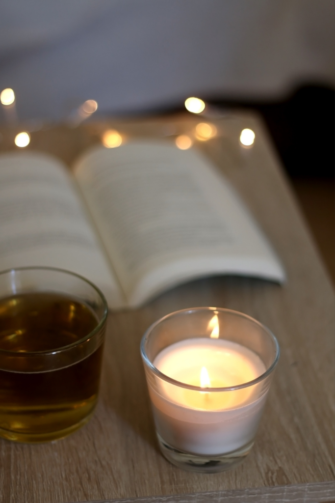 Image of open book, lit candle and fairy lights on a desk